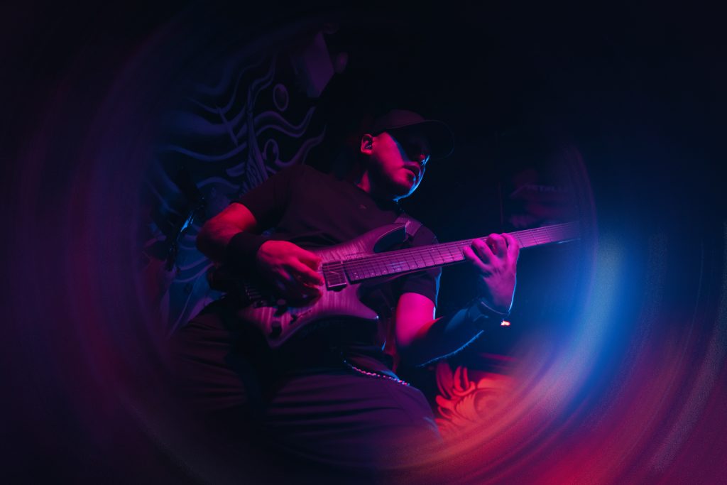 AL Javier, founder and guitarist of BLOODFATE, playing guitar under red and blue light