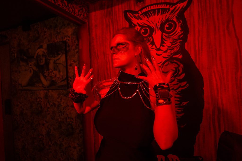 Emilie Bienne posing in front of a painted owl in red light