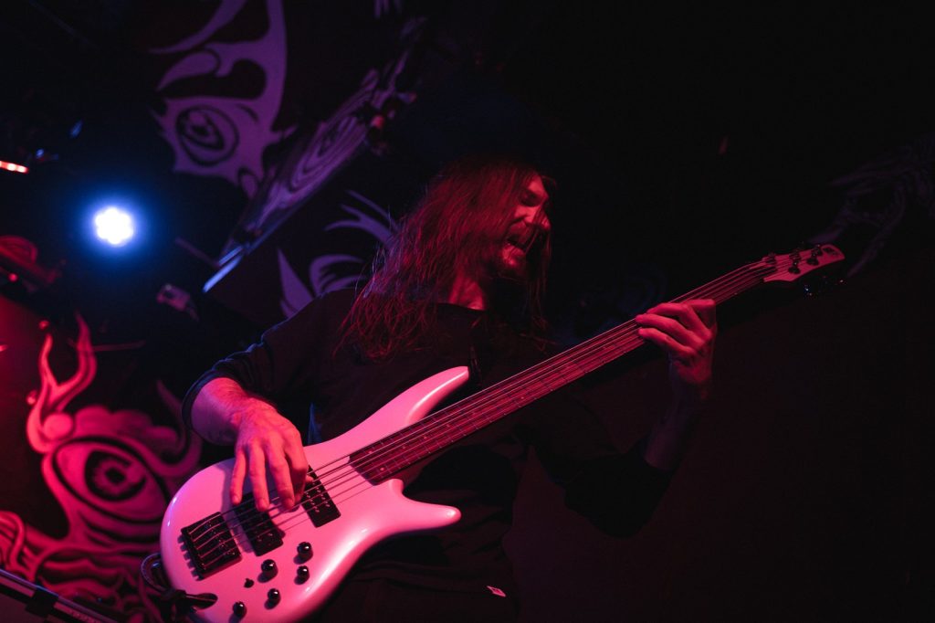 Philippe of BLOODFATE playing bass live in New York under red stage light